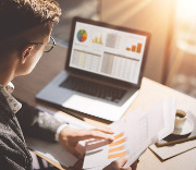 Image of man looking at graphs on a paper and computer screen