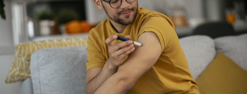 Photo of a man giving himself an insulin shot at home